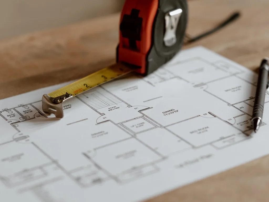 Plan de maison, mètre ruban et stylo pour l'étude du projet de chauffage